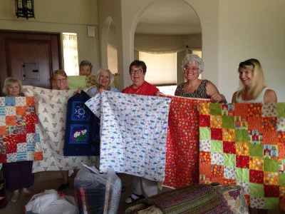 Nifty Needles SYNC Group 1 Nifty Needles SYNC Group members holding up quilts they have made for charity