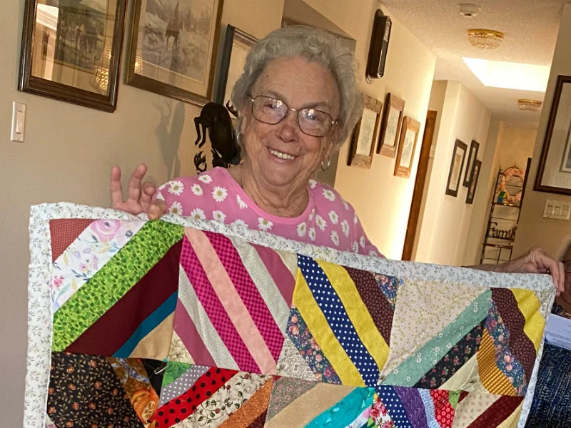 Pat Eby from the Nifty Needles Quilt group holds up a quilt